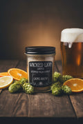 A clear glass jar candle with a black screw-top lid and a black label reading 'WICKED LION SCENTED PALM CANDLE' and 'LIONS BREW', photographed on a plain light background.