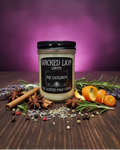 Wicked Lion candle with spices and herbs on a wooden surface against a purple background
